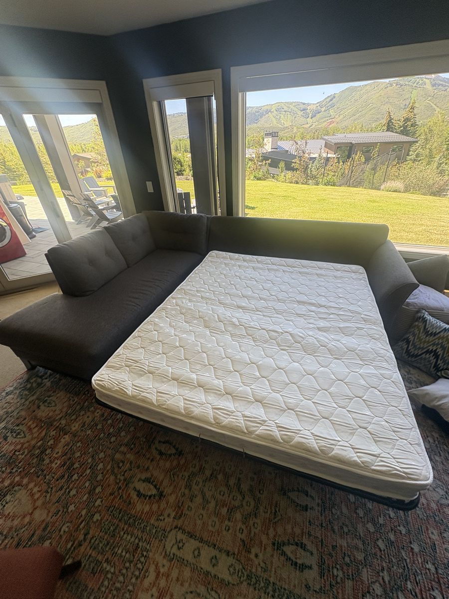 Large grey couch which can also fold out into a queen mattress