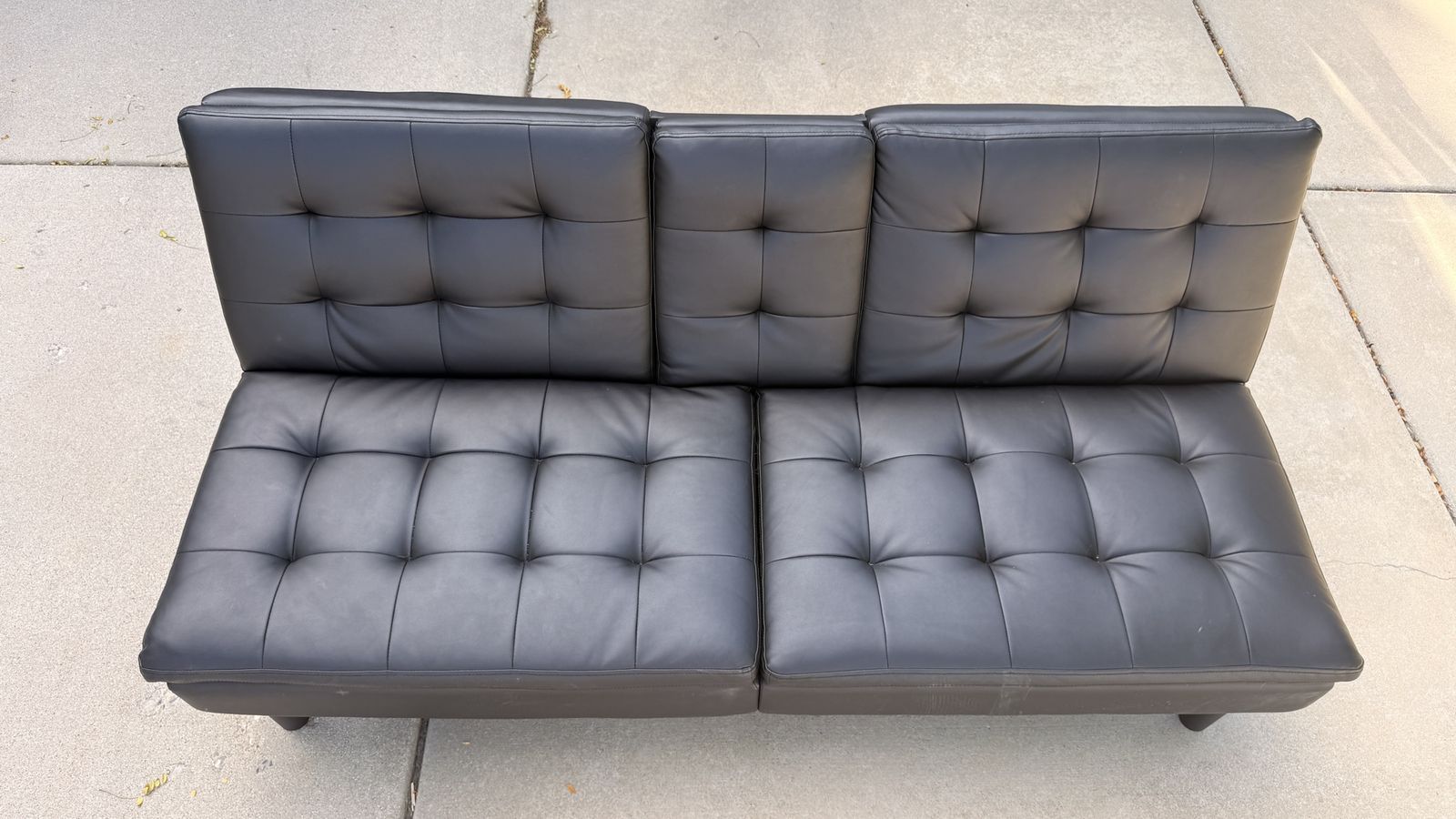 Black Faux Leather Tufted Futon Sofa with Drop-Down Cupholders. 