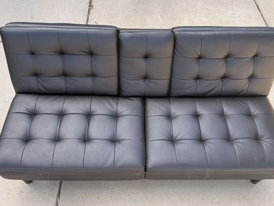 Black Faux Leather Tufted Futon Sofa with Drop-Down Cupholders.