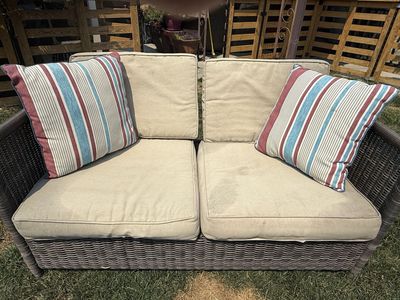 Outdoor Wicker Loveseat with Beige Cushions & Striped Throw Pillows
