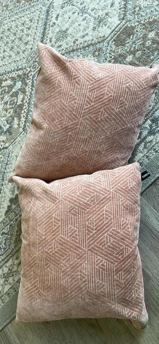 pair of dusty rose pink throw pillows featuring an intricate geometric triangle and diamond woven jacquard pattern.