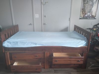 Twin sized bed with drawers and wood frame.