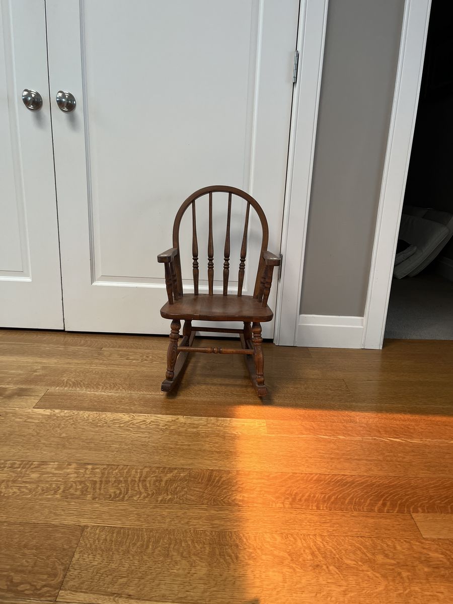 Solid wood, vintage child’s rocking chair with small flowers painted on arms.