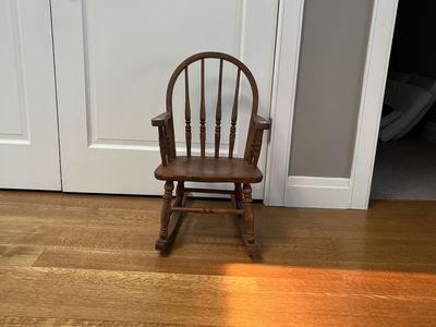 Solid wood, vintage child’s rocking chair with small flowers painted on arms.