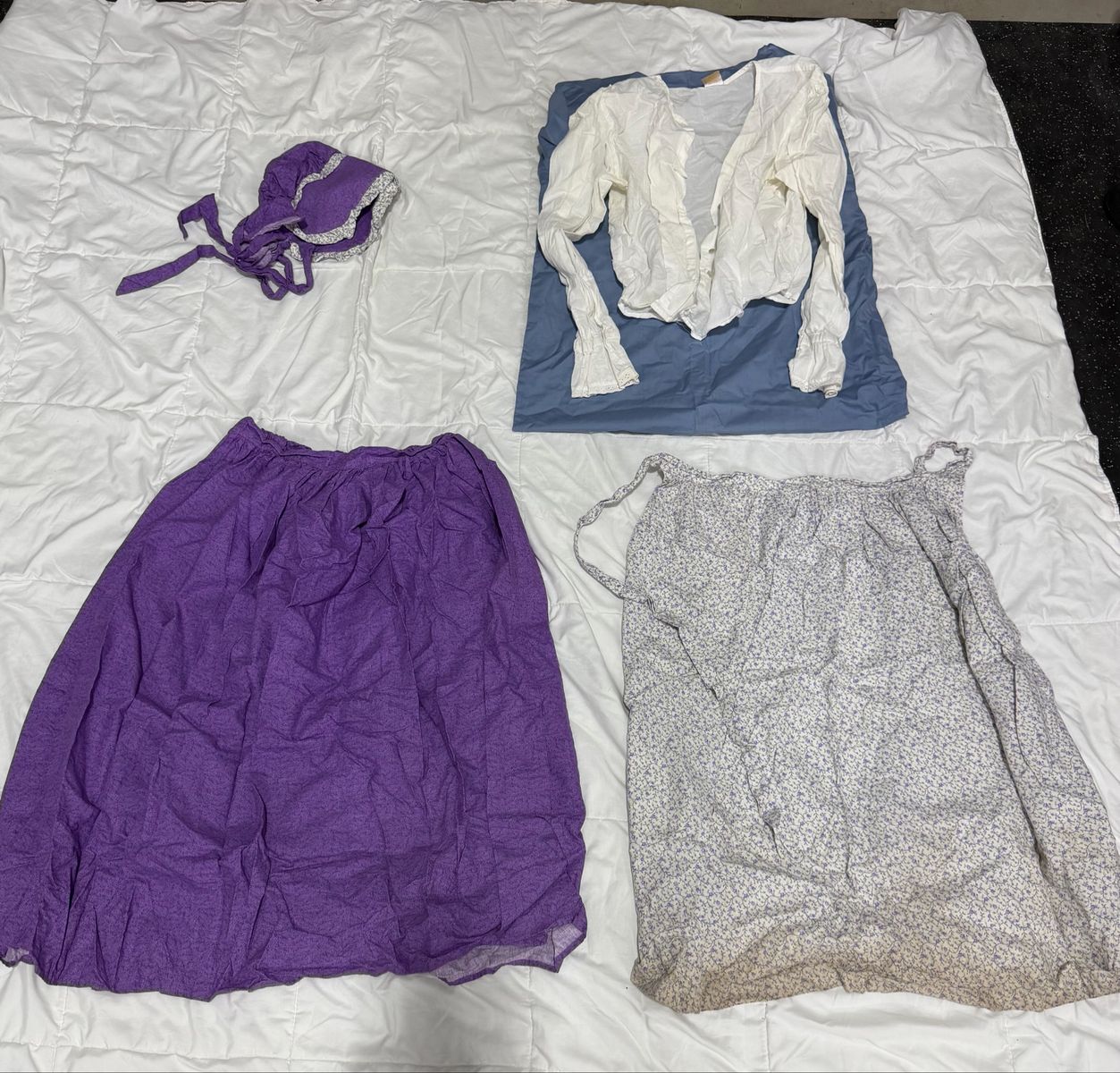 Purple pioneer skirt and bonnet with white blouse and color coordinated apron.