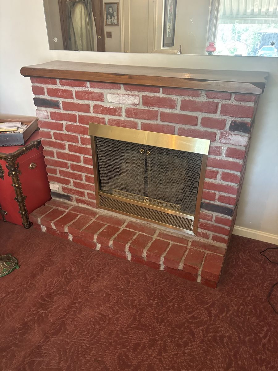 Red Brick Fireplace with Wooden Mantle and Brass Fire Screen.