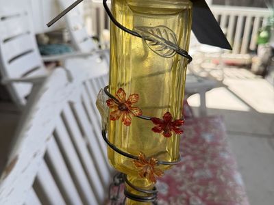 Hanging Yellow Glass Bottle Hummingbird Feeder with Metal Roof and Floral Accents