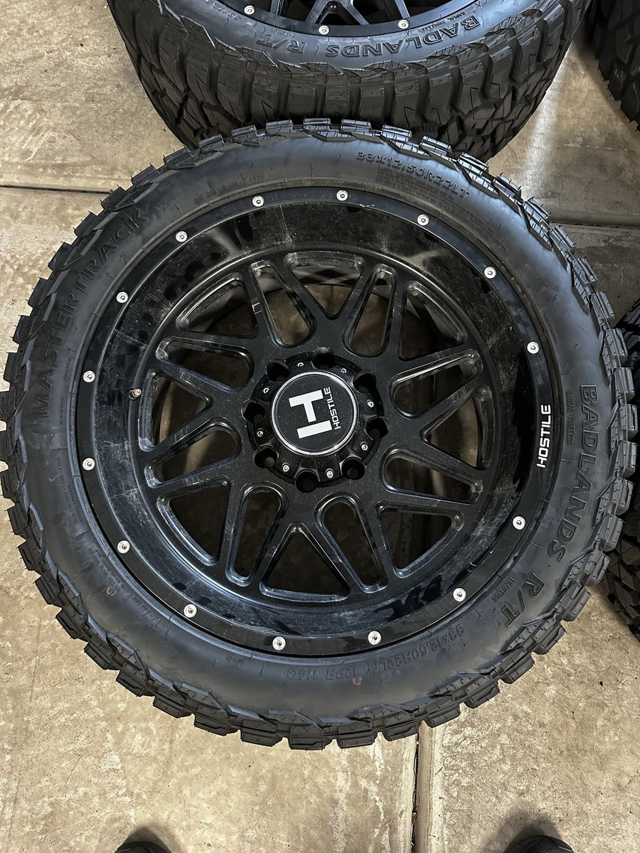 Hostile Black Wheels with Mastertrack Badlands R/T 33x12.50R22LT Tires - Set of 4