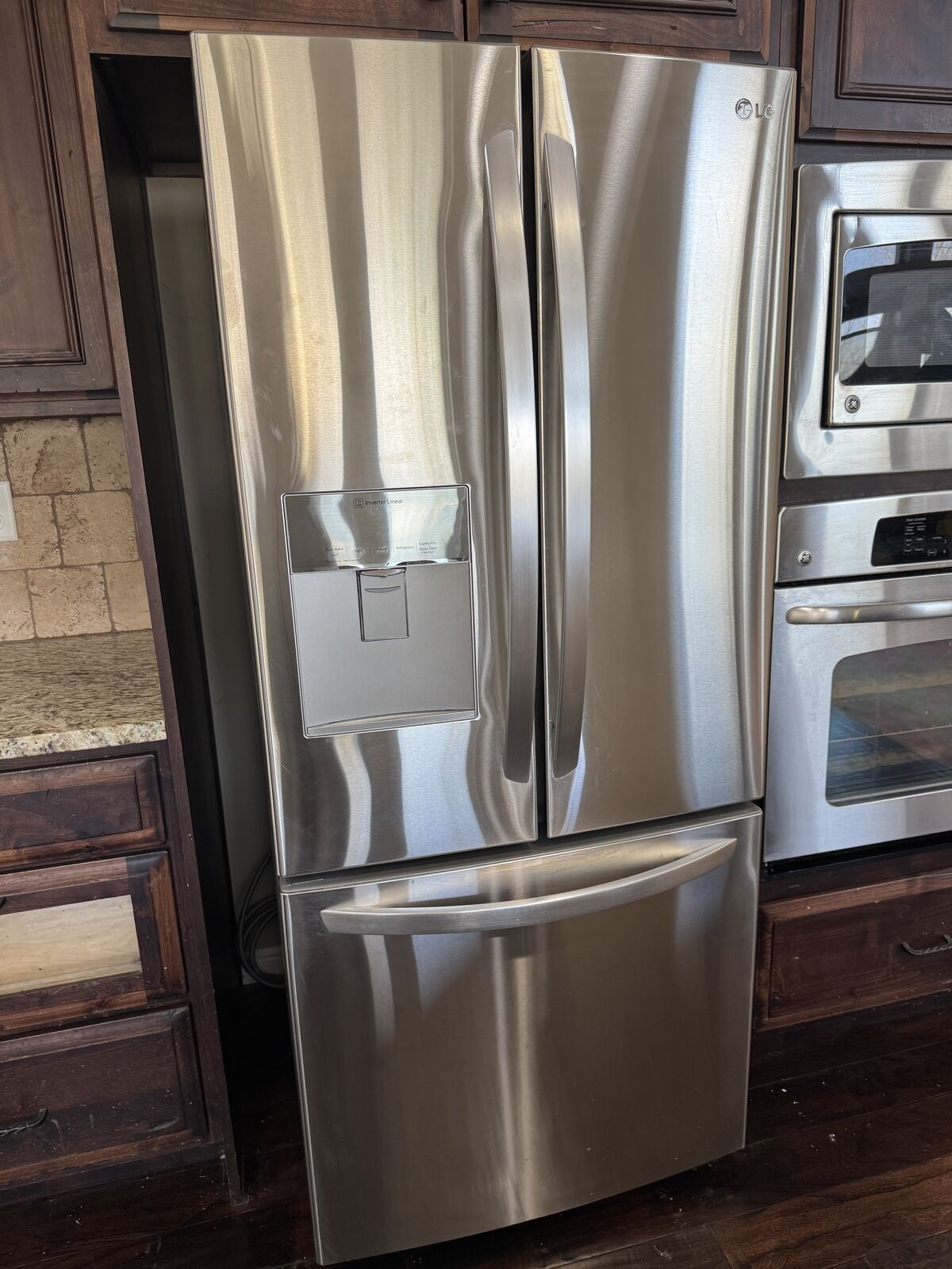 stainless-steel LG French-door refrigerator with a bottom freezer and external water/ice dispenser.