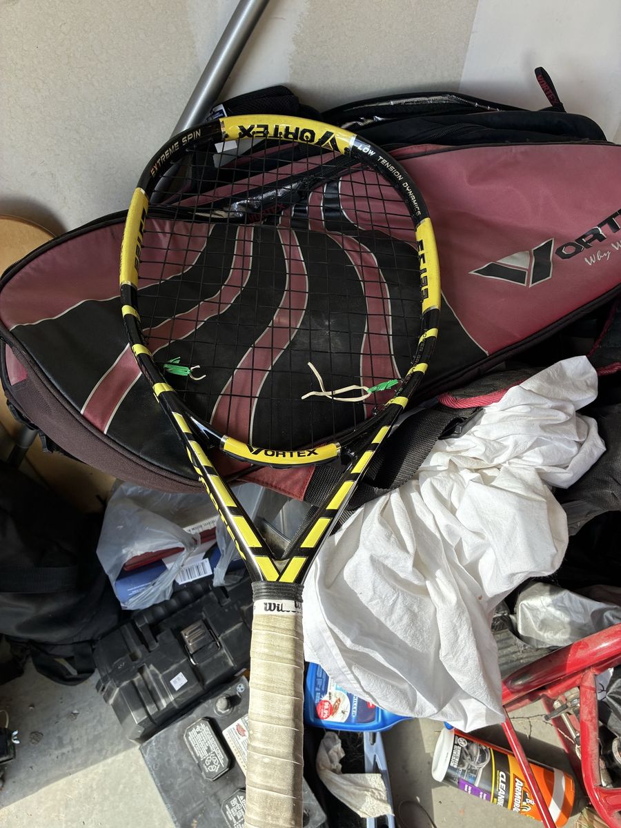 Three tennis rackets with bag miscellaneous stuff in the bag