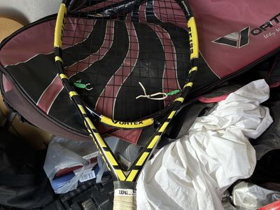 Three tennis rackets with bag miscellaneous stuff in the bag