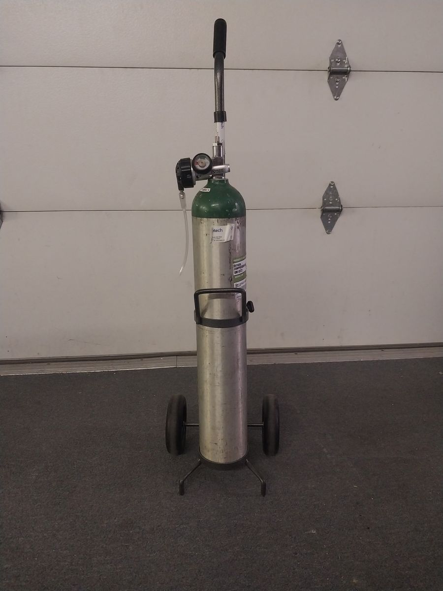 Medical-grade oxygen tank with cart and regulator.