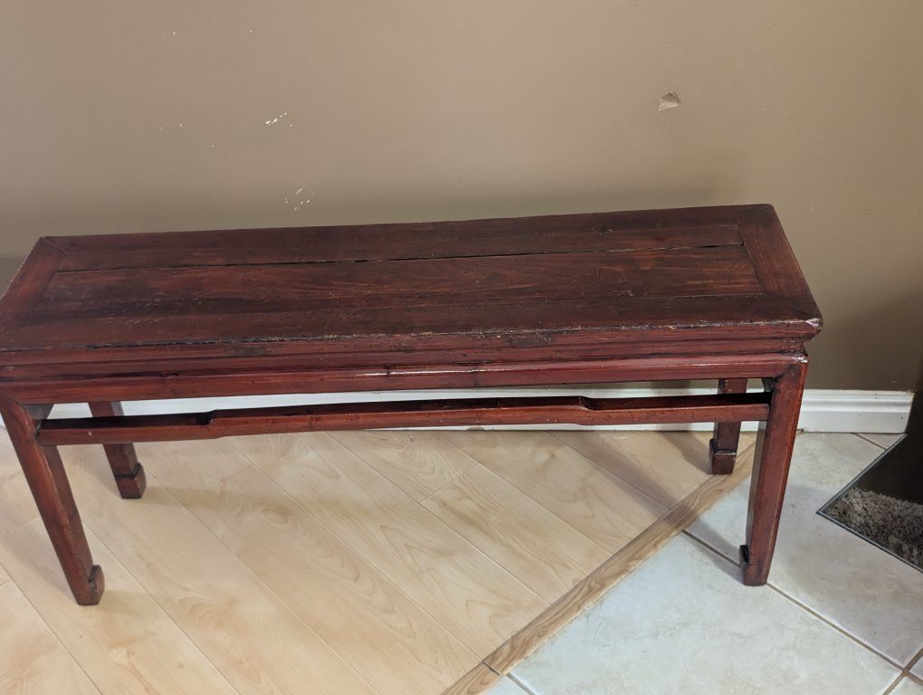 This dark red Chinese wine table features a rectangular top and tapered legs joined by stretchers.