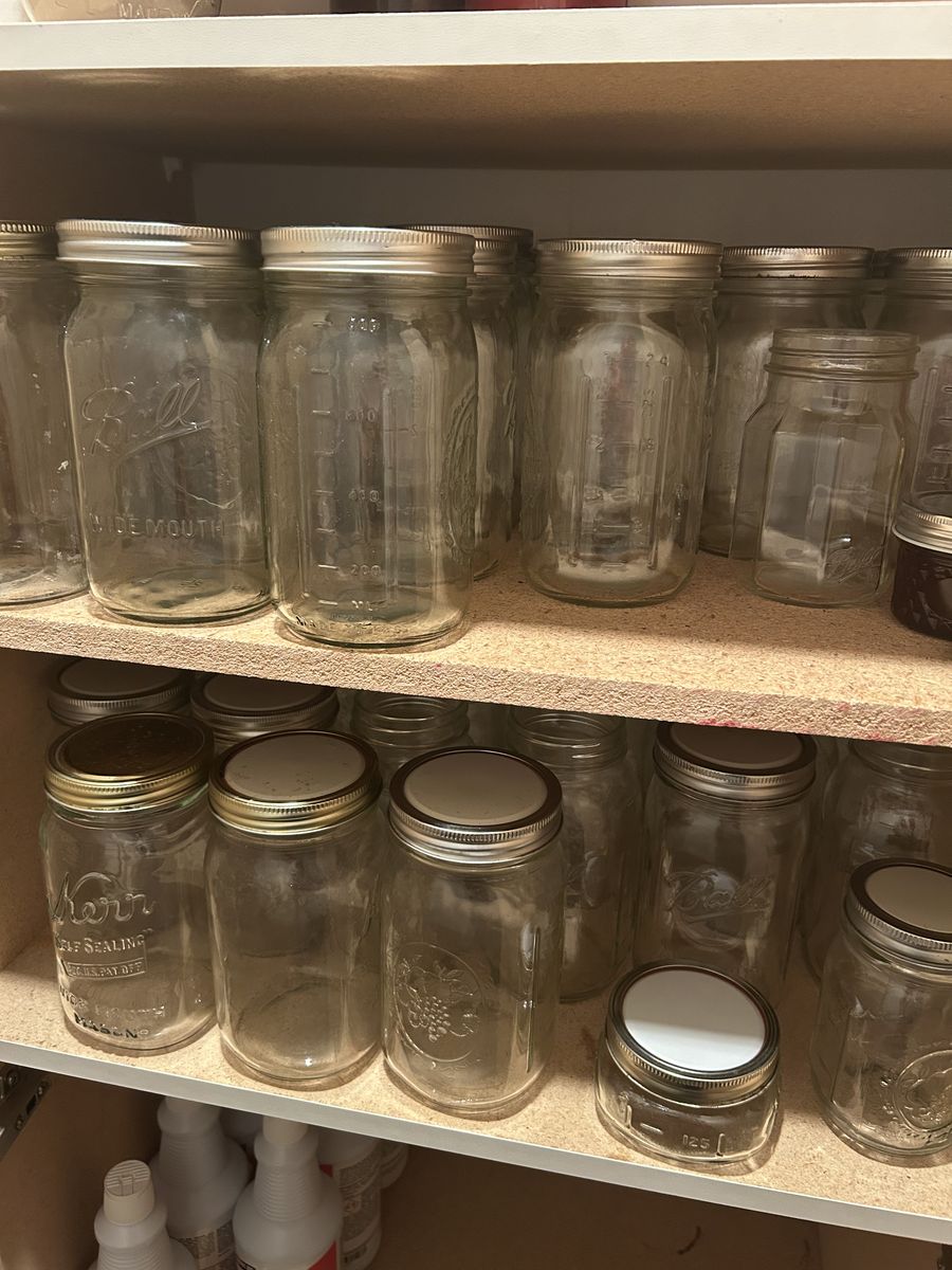 Dozens of assorted Mason jars, lids, and canning cooking pot.