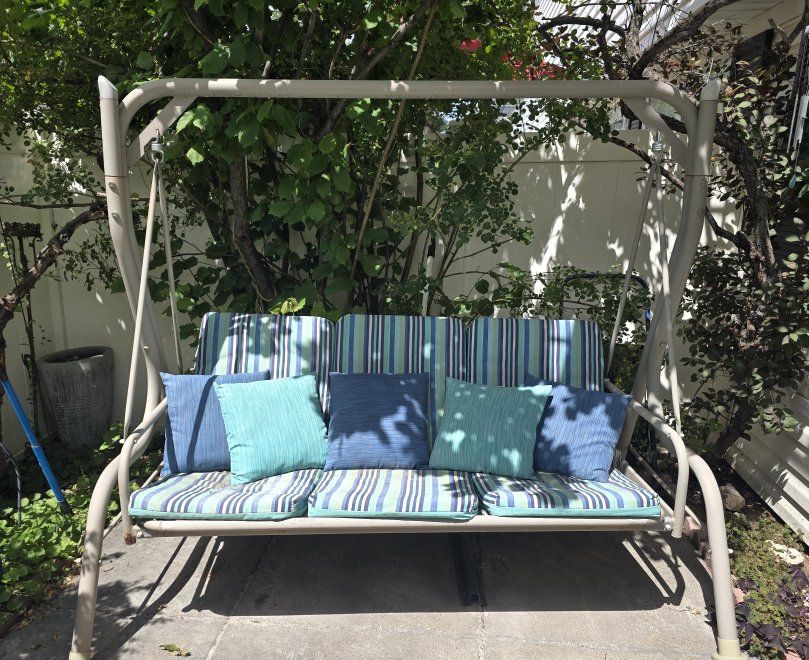 Outdoor Patio Swing with Striped Cushions and Accent Pillows - Perfect for Relaxing.