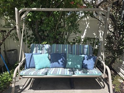 Outdoor Patio Swing with Striped Cushions and Accent Pillows - Perfect for Relaxing.