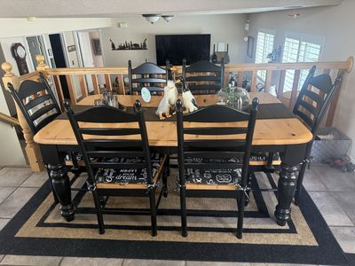 Selling a beautiful, solid, pine dining table with a warm honey finish, paired with six matching black wooden chairs.
