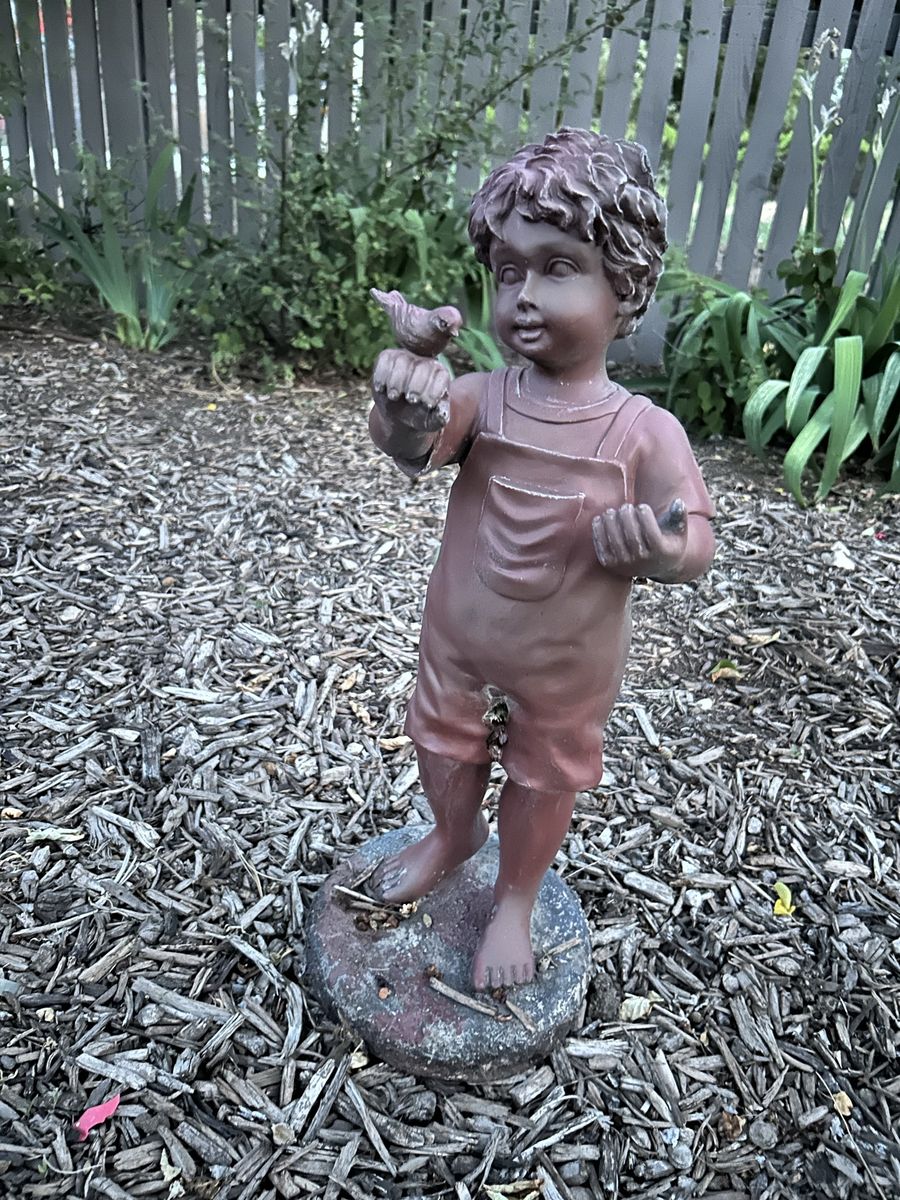 Garden statue. Child with bird