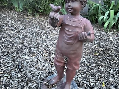 Garden statue. Child with bird