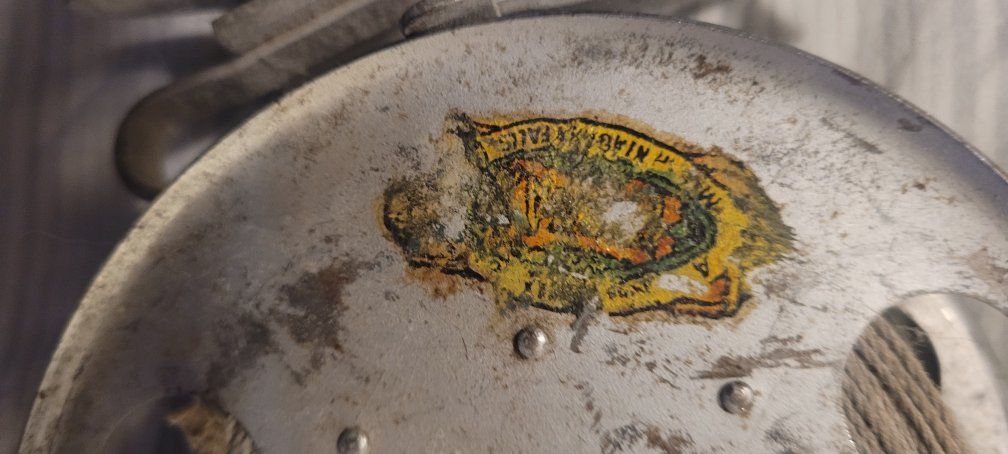 Vintage Metal Fishing Reel with Worn Label - Used Condition