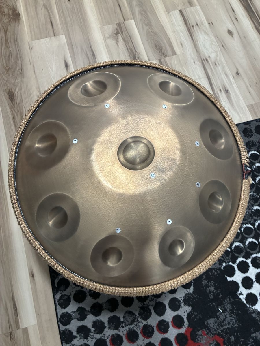 9-note handpan drum with backpack, stand, mallets, and instruction manual.
