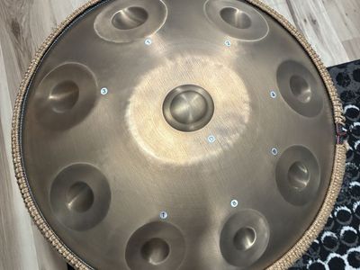 9-note handpan drum with backpack, stand, mallets, and instruction manual.