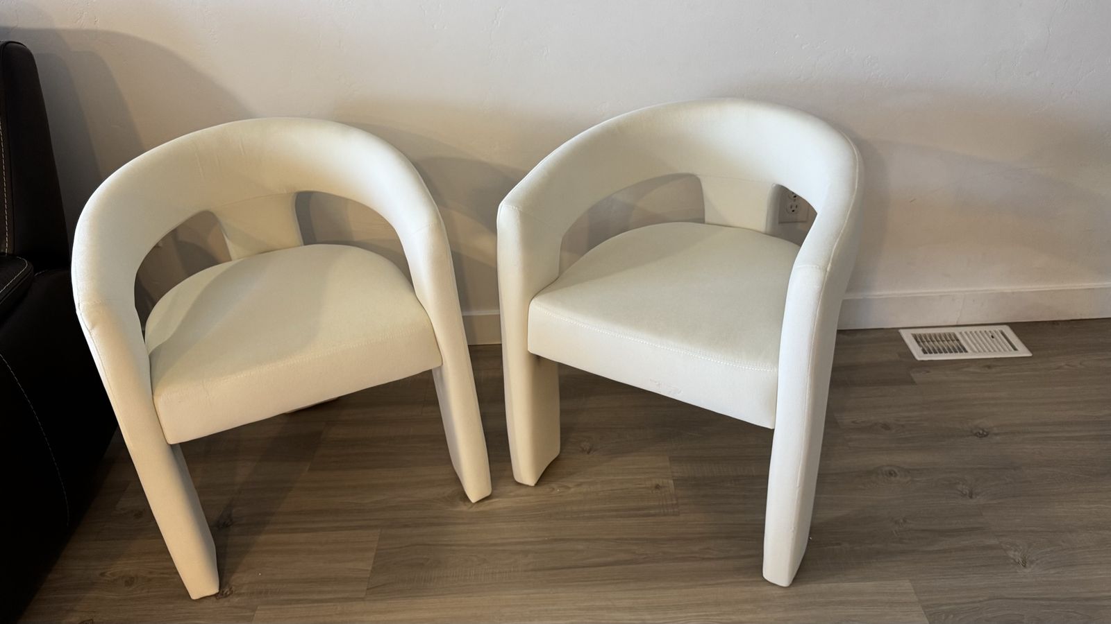 Rounded "barrel-style" dining chair with an open back and three legs — a modern upholstered chair