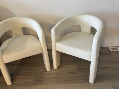 Rounded "barrel-style" dining chair with an open back and three legs — a modern upholstered chair