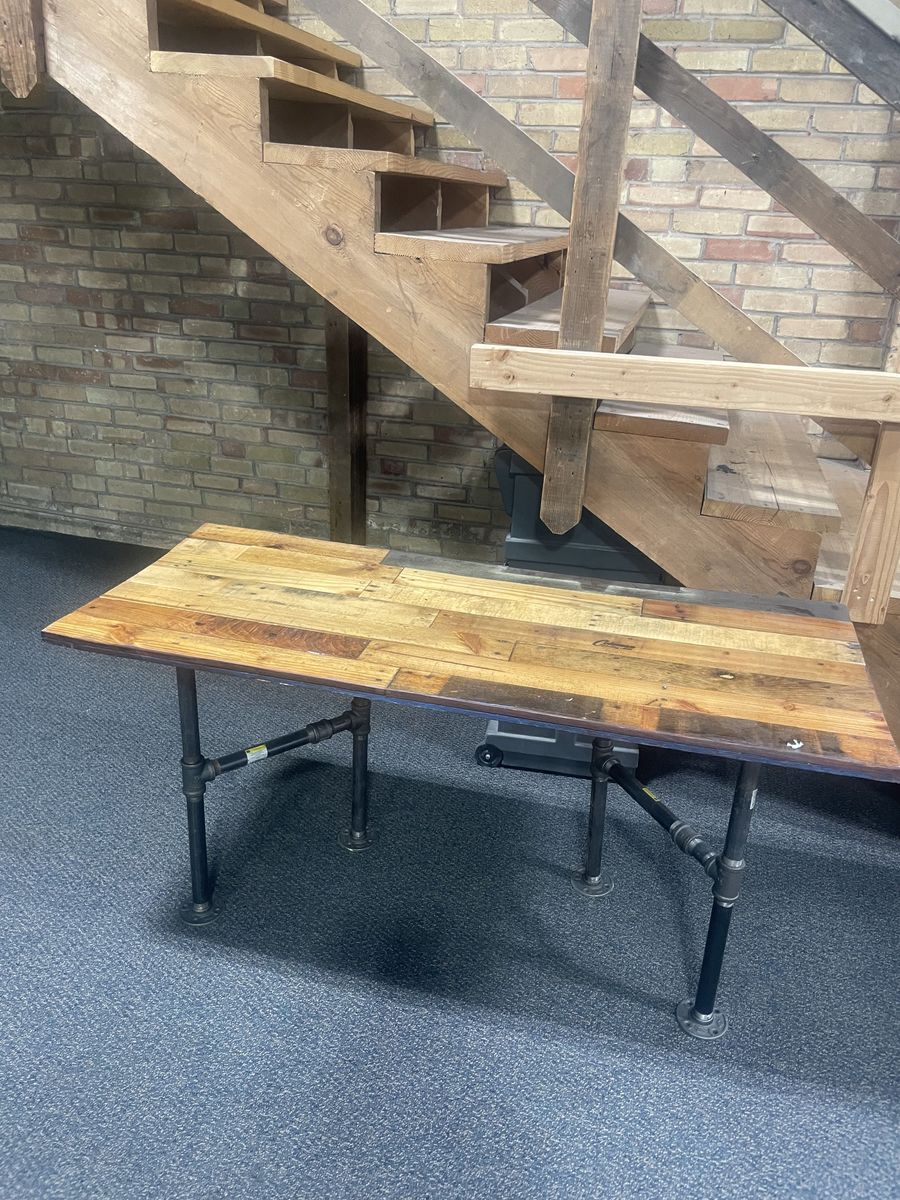 Table with wood finished top and pipe legs