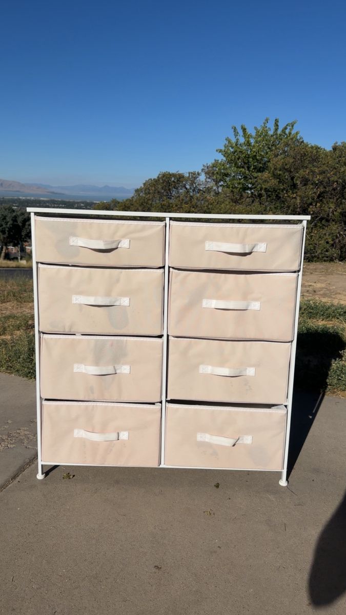 Versatile storage dresser has a white steel frame with a hard wood top and eight removable pink fabric drawers.