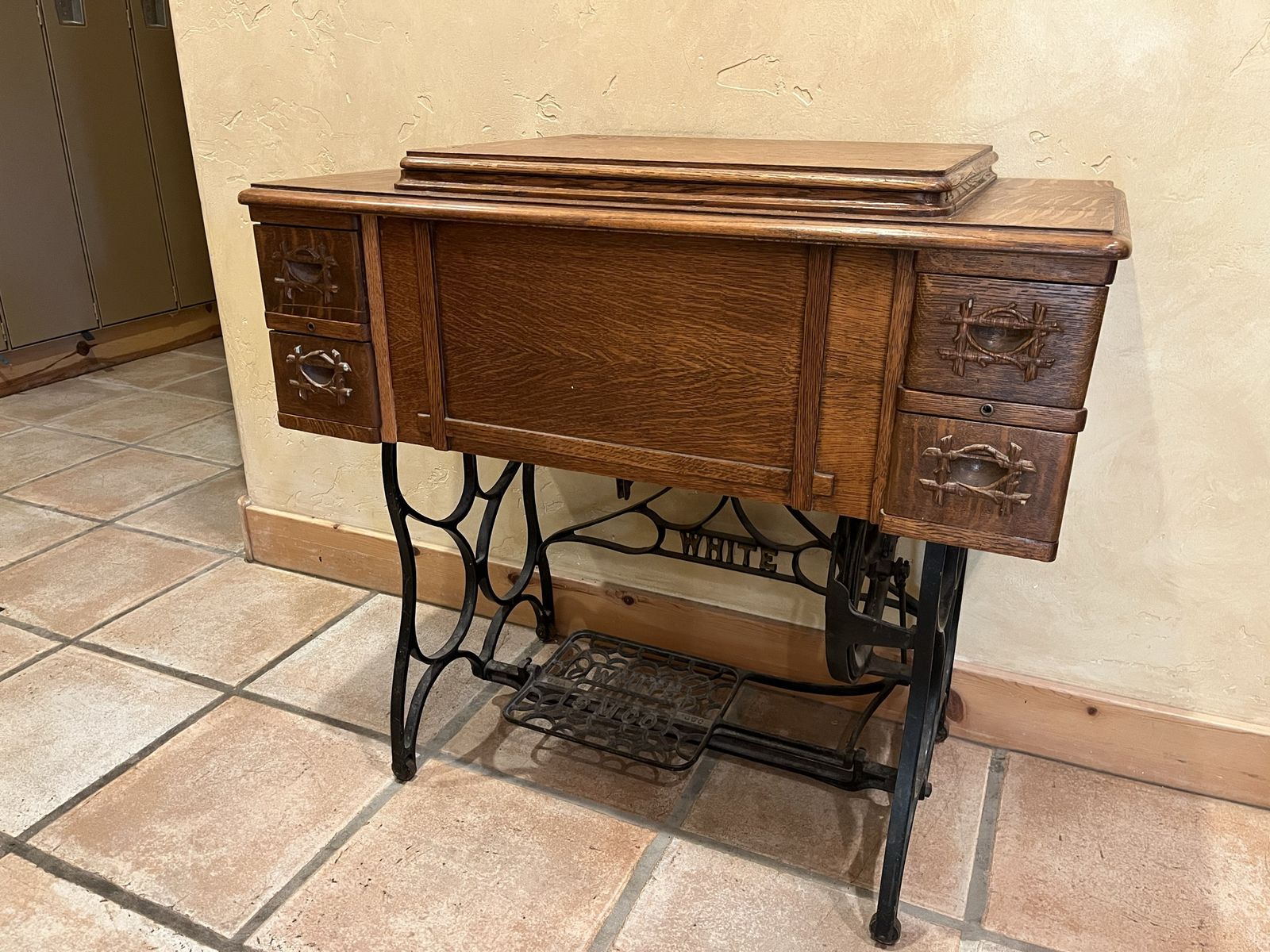 Antique White treadle sewing machine. 4 drawer cabinet. Attachments included.