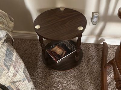 small round wooden end table with a lower shelf (often called a two-tier accent table).