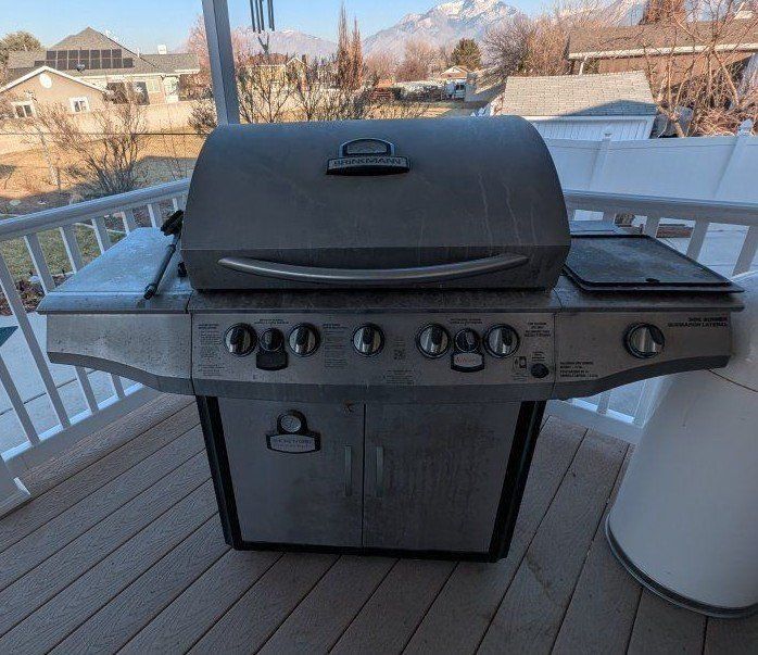 Smoke n' Grill Professional 5 Burner Gas Grill with Smoker and Propane Tank with a cover.