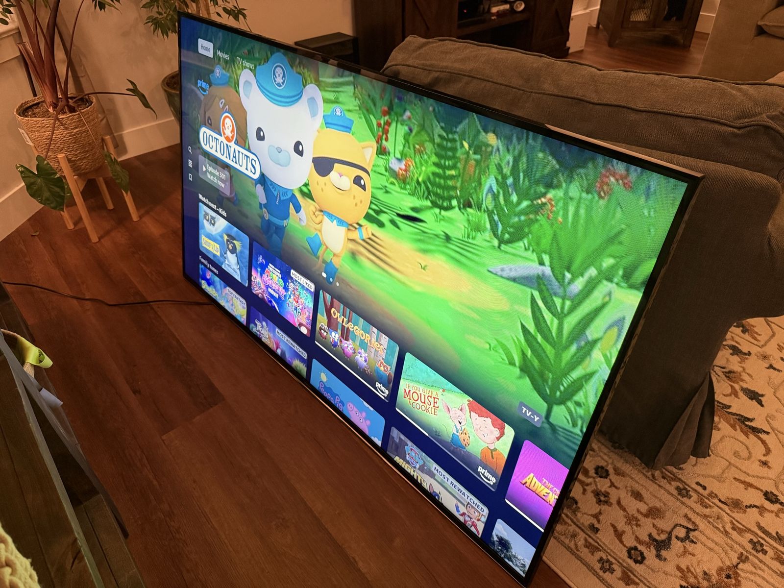 65 inch Samsung TV, Brown Faux Leather Two-Cushion Loveseat sleeper, and a futon. 