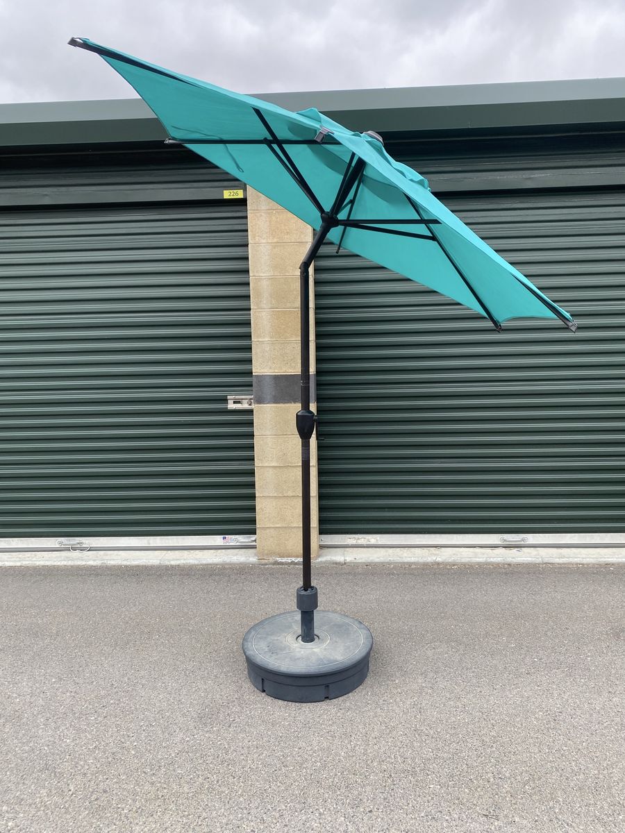 Teal patio umbrella with weighted stand.
