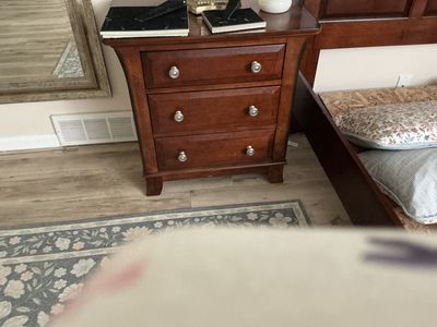 Queen sized wooden bed with side rails and footboard and nightstand.