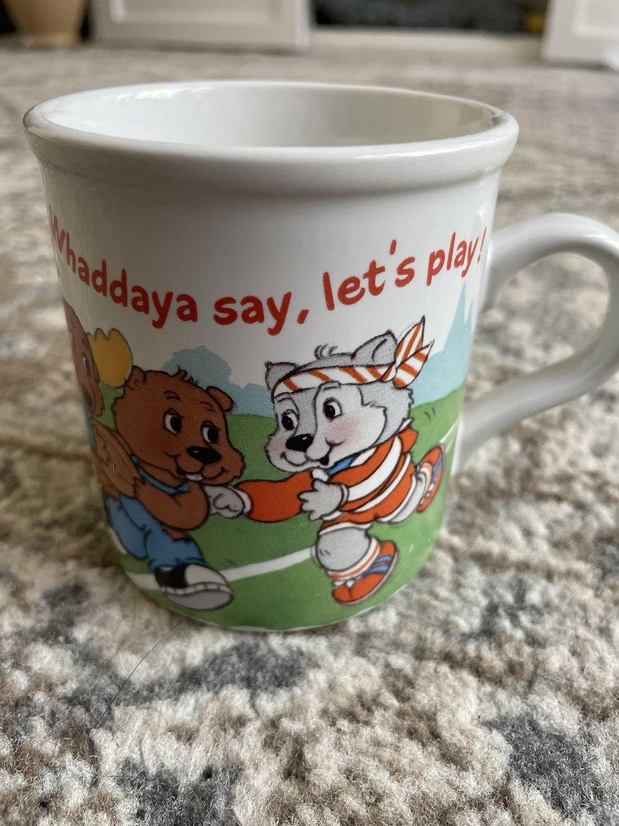 This vintage stoneware coffee mug features characters from The Get Along Gang and was produced by American Greetings in 1985