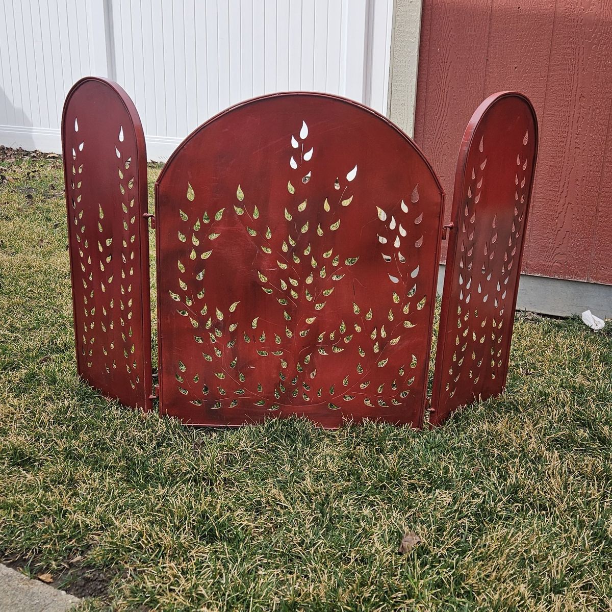 Red metal fireplace screen, leaf cutouts