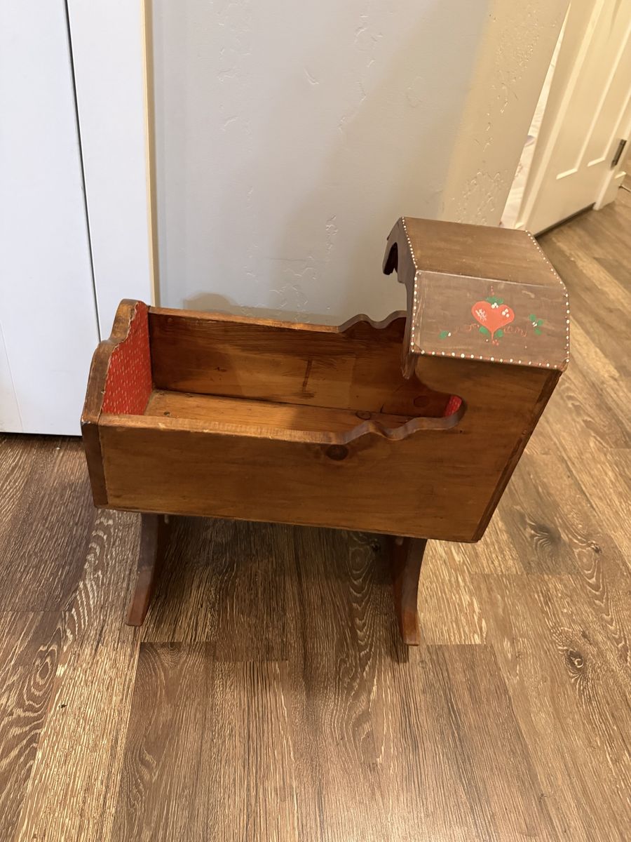 vintage wooden rocking doll cradle features hand-painted strawberry decals and a red patterned