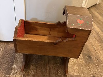 vintage wooden rocking doll cradle features hand-painted strawberry decals and a red patterned