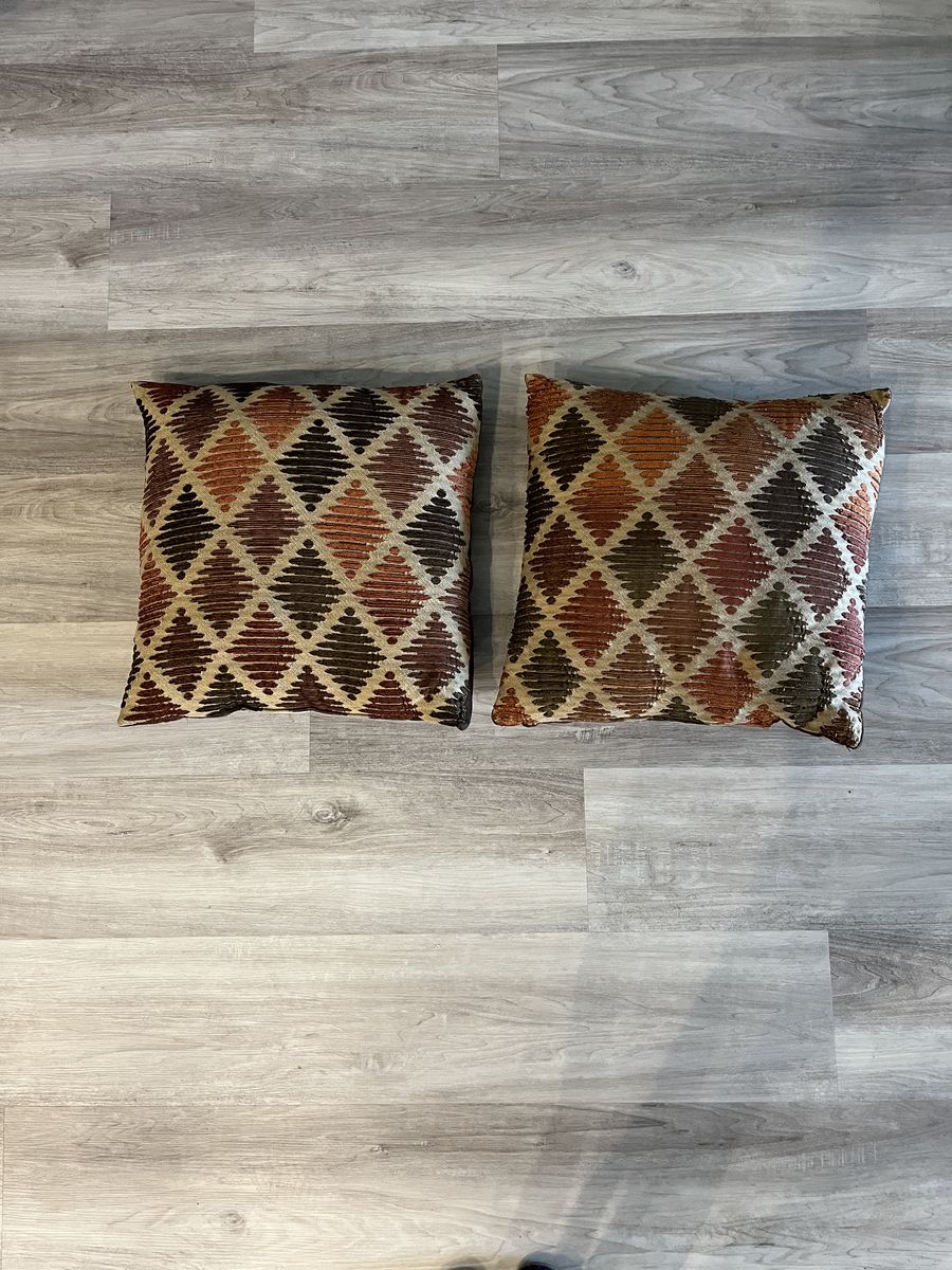 Two large 20 x 20 pillows in the colors of orange, brown and tan.