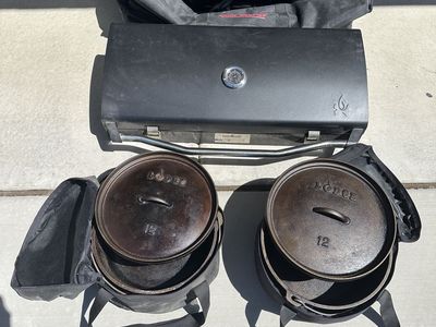 Camp Chef Explorer 2-Burner Stove, Deluxe BBQ grill box, and 2 Lodge 12" Dutch Ovens with cases.